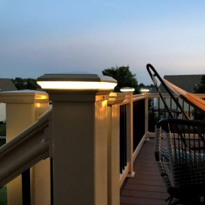 Outside deck lighting on a post cap with a hammock and fire pit in the background.